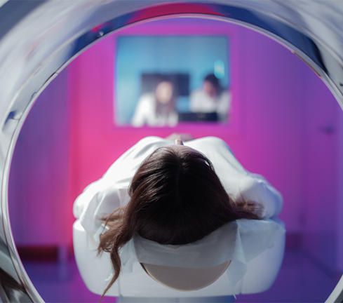 Woman going into an MRI machine, featured image for Iron rim lesions and MS