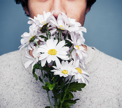 Man smelling a bunch of daisies, featured image around smell and MS