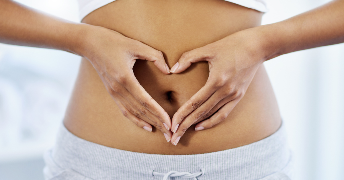 Image of a woman's stomach holding her hands in a heart, featured image to illustrate ways to improve gut health