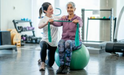 Older woman exercising in a gym with a physiotherapist for her MS