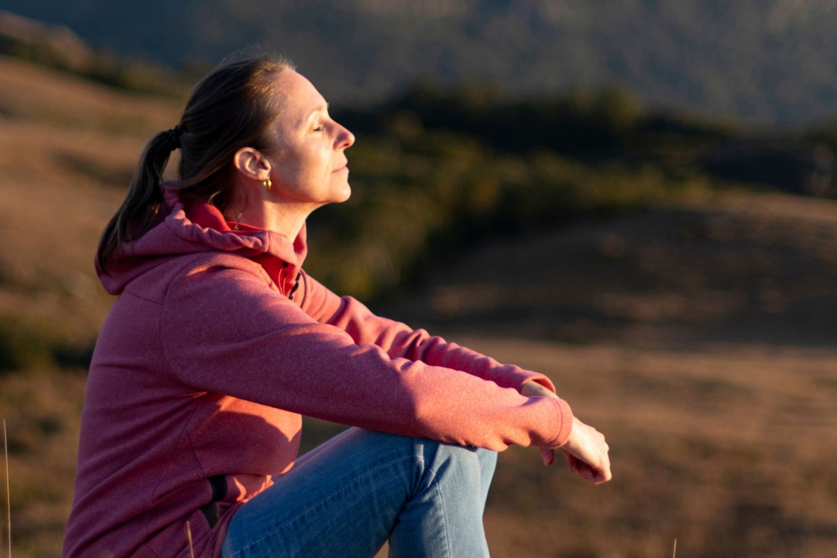 Young woman sitting in the sunset with her eyes shut thinking mindfully